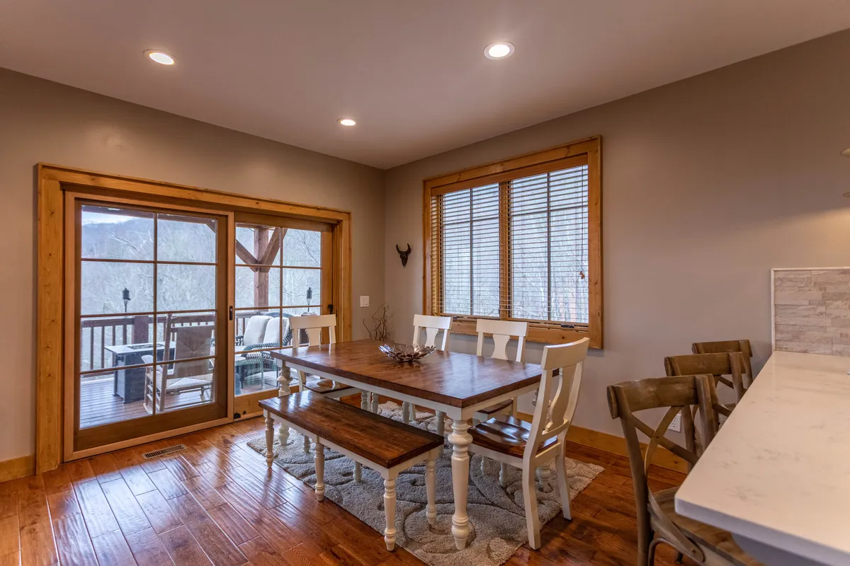 A bright, welcoming dining area with a spacious table and large windows offering mountain views. Wooden flooring and simple decor create an inviting space ideally suited for shared meals and gatherings.
