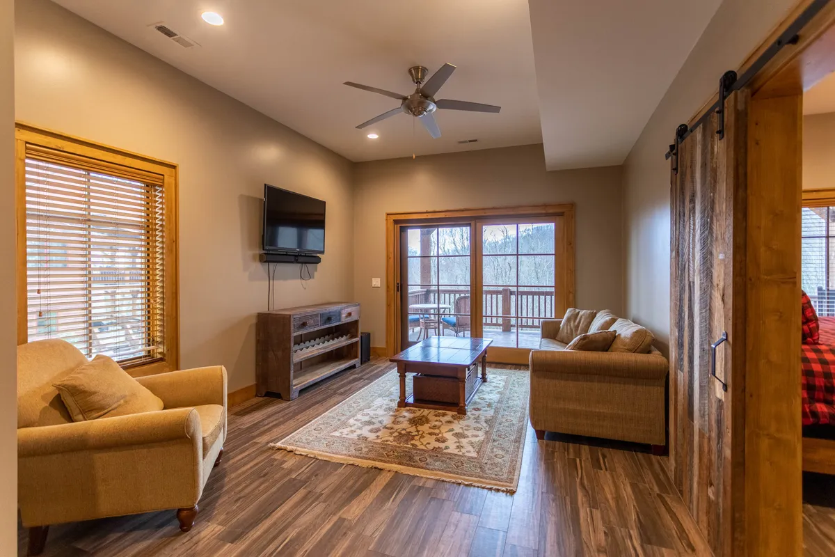 This image presents a comfortable media lounge setup, with a plush sofa, a coffee table perfect for snacks or board games, a TV for movie nights, and a window offering a glimpse of the view outside. The arrangement invites relaxation and shared experiences.