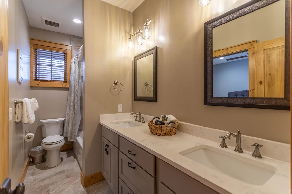 A modern bathroom featuring a double sink vanity, large framed mirrors, and a spacious shower area. The mood is calm and functional, supporting refreshing morning routines or winding down at night.